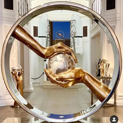 La main a poli l'acier inoxydable de miroir gardant les sculptures en terre